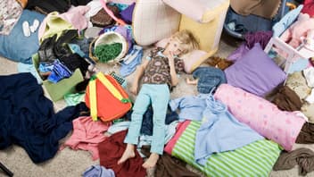Kind liegt in chaotischem Kinderzimmer auf dem Boden.