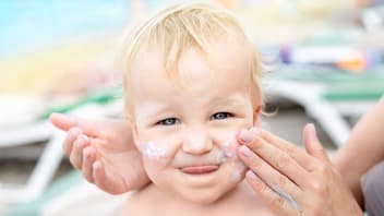 Baby wird mit Sonnencreme eingeschmiert.