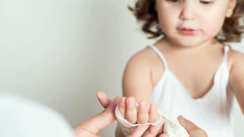 Kind bekommt einen Verband um die Hand.