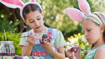 Zwei Kinder bemalen Ostereier im Garten.