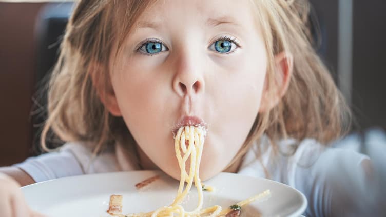 Ein Mädchen isst Spaghetti.
