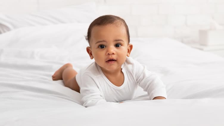 Ein Baby krabbelt auf dem Bett.
