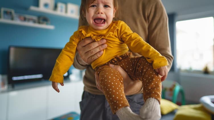 Kind schreit auf Papas Arm.