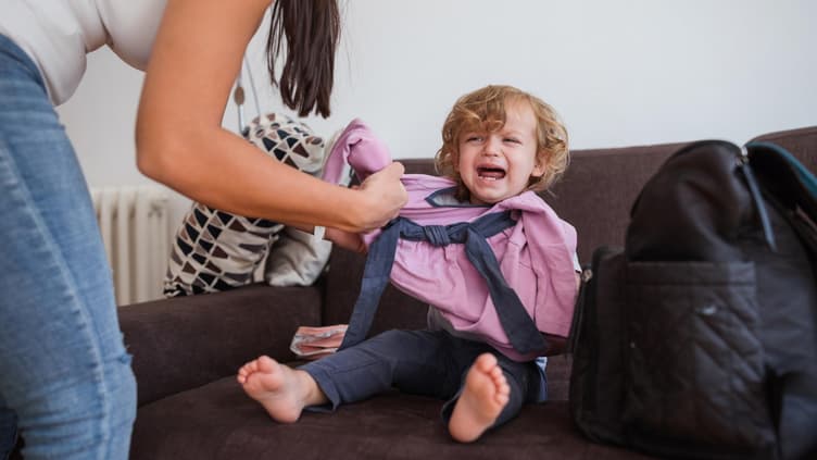 Mutter zieht weinendes Kind an.