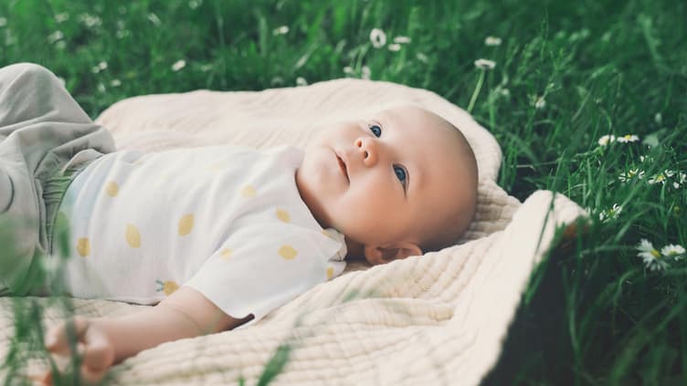 Baby liegt auf einer Wiese.