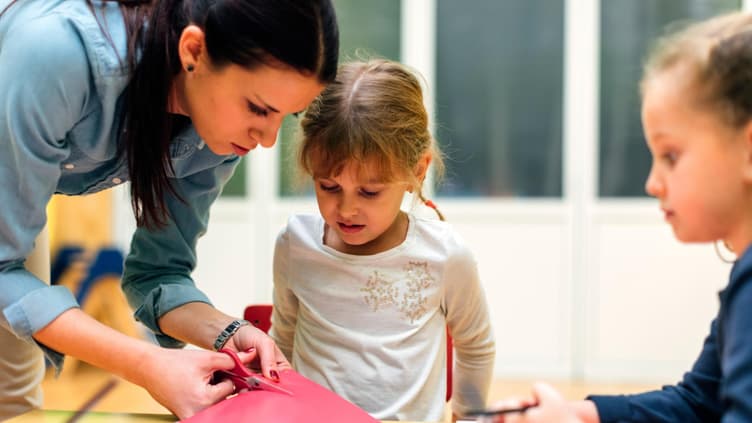 Erzieherin bastelt mit Kindern.