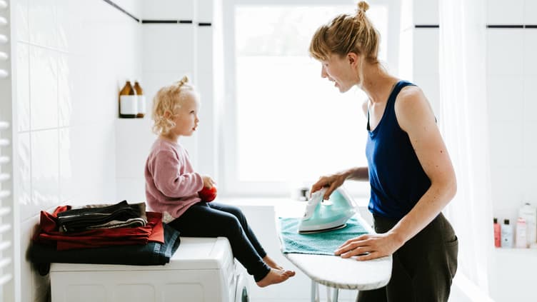 Mutter bügelt und spricht mit Tochter.