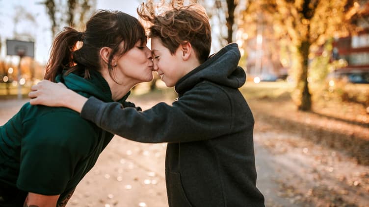 Eine Mutter küsst ihren Teenager-Jungen zärtlich auf die Nase. 