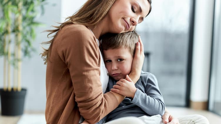 Liebevolle Mutter, die ihren traurigen Sohn zu Hause tröstet.