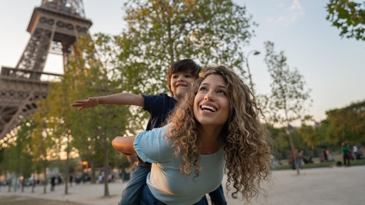 Eine Mutter und ihr Sohn spielen vor dem Eiffelturm in Paris, Frankreich. 
