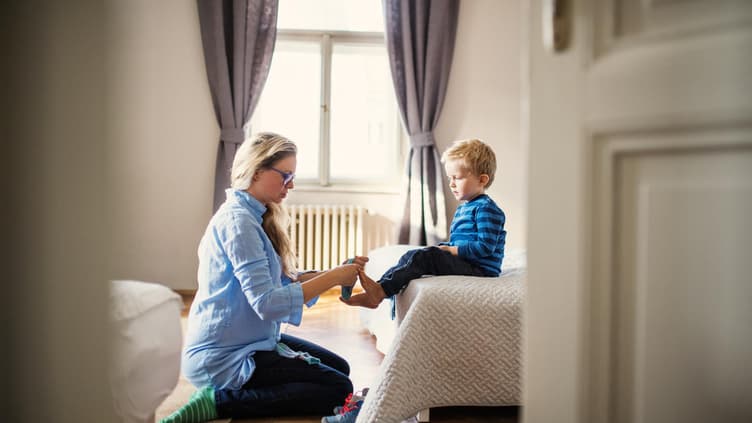 Mutter zieht ihrem Sohn die Socken an.