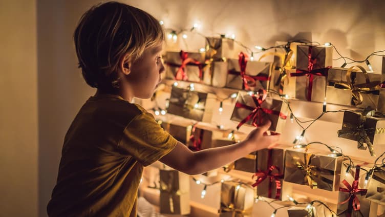 Ein kleiner Junge öffnet ein Türchen seines Adventskalenders. 