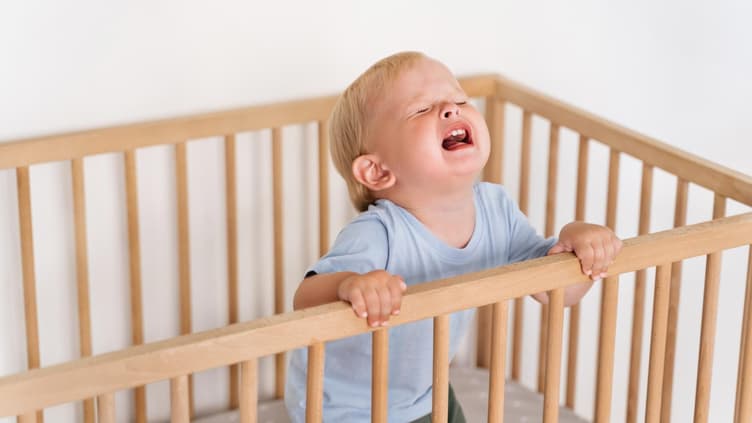 Ein Kleinkind wird im Kinderbett wütend