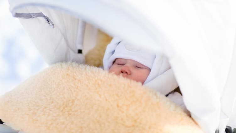 Baby schläft im Winter draußen im Kinderwagen.
