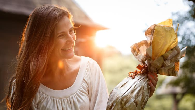 Eine Frau bekommt ein Ostergeschenk überreicht und freut sich.