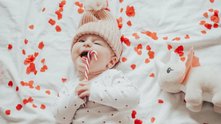 Baby liegt im Bett voller Herzen.
