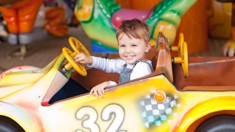 Ein kleiner Junge im Auto im Freizeitpark.