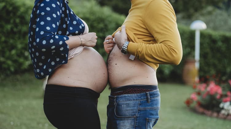 Schwangere Frau und ihr Mann halten ihre Bäuche aneinander.