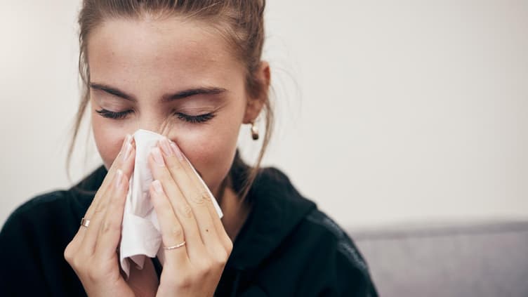 Frau putzt sich die Nase.