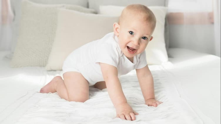Ein kleiner Junge kniet auf dem Bett.