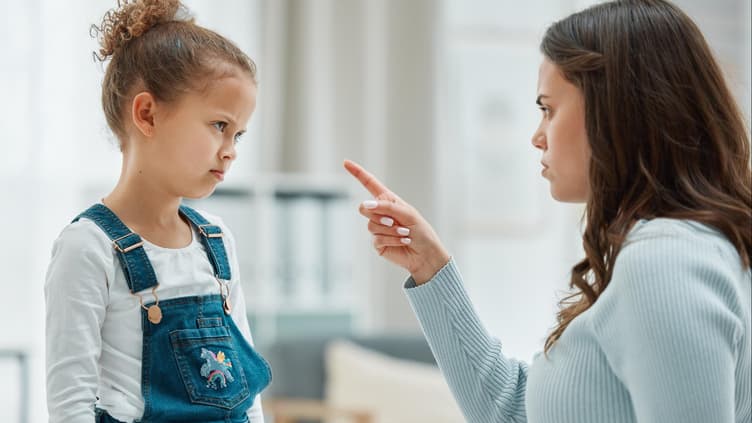 Mutter schimpft mit erhobenem Zeigefinder mit ihrer Tochter.