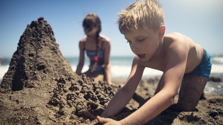 Kinder buddeln am Strand.