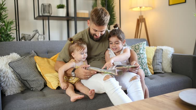 Vater schaut sich mit zwei Kindern Fotoalbum an.