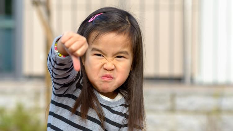 Kind hält den Daumen nach unten.