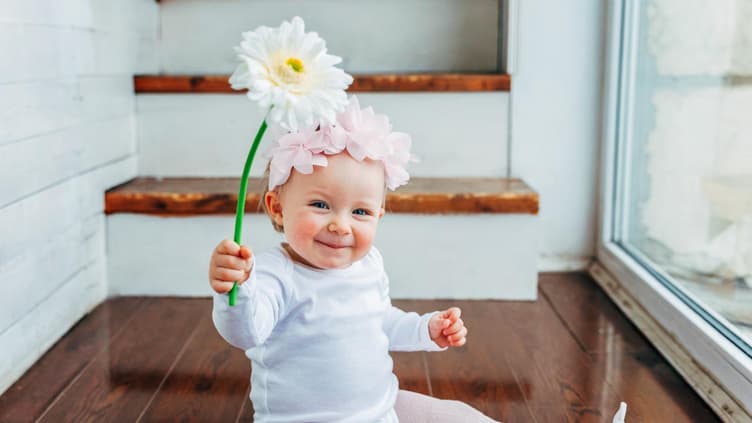 Ein kleines Baby, das eine Blume hält. 