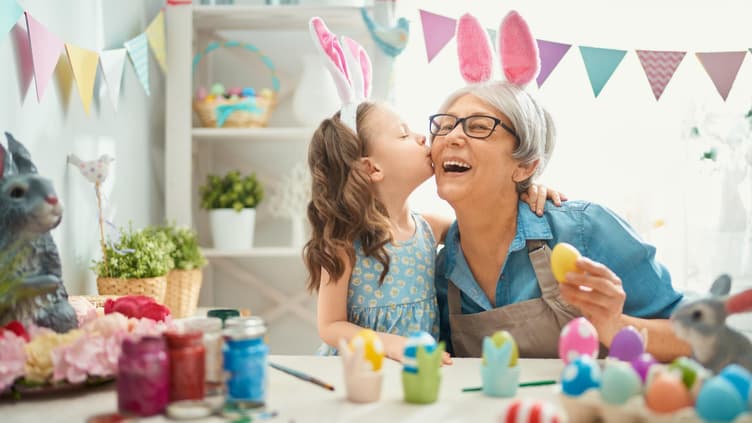 Enkeltochter gibt Oma einen Kuss, beide tragen Hasenohren.