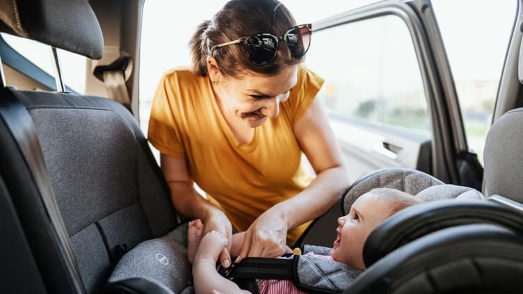 Eine Mutter schnallt ihr Baby im Auto an. 