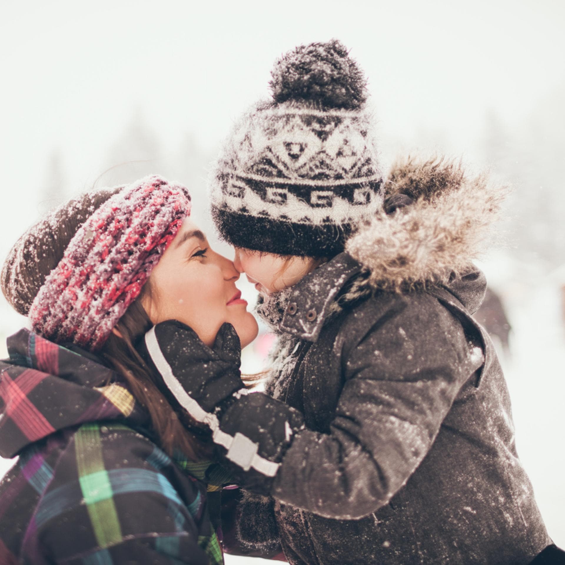 Mama und Kind Nase an Nase im Schnee.
