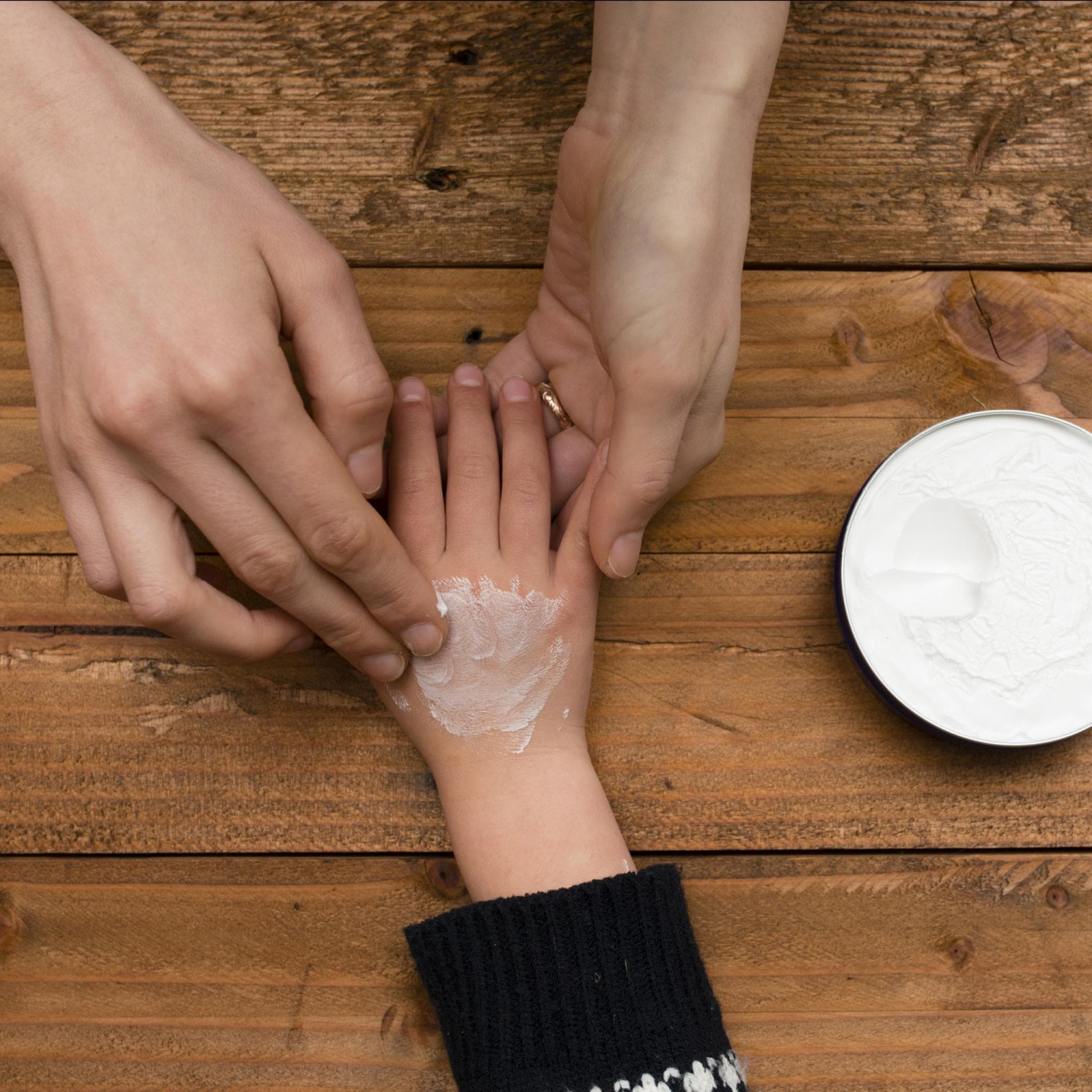 Eine Mutter cremt ihrem Kind die Hände ein. 