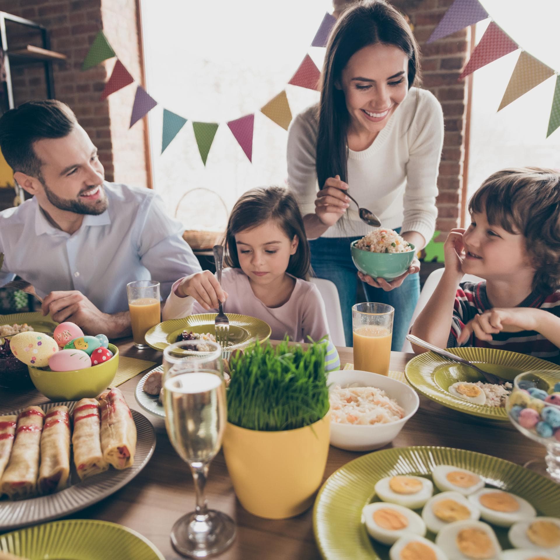 Vater und Mutter genießen ihr Osterfrühstück mit ihrer Tochter und ihrem Sohn.