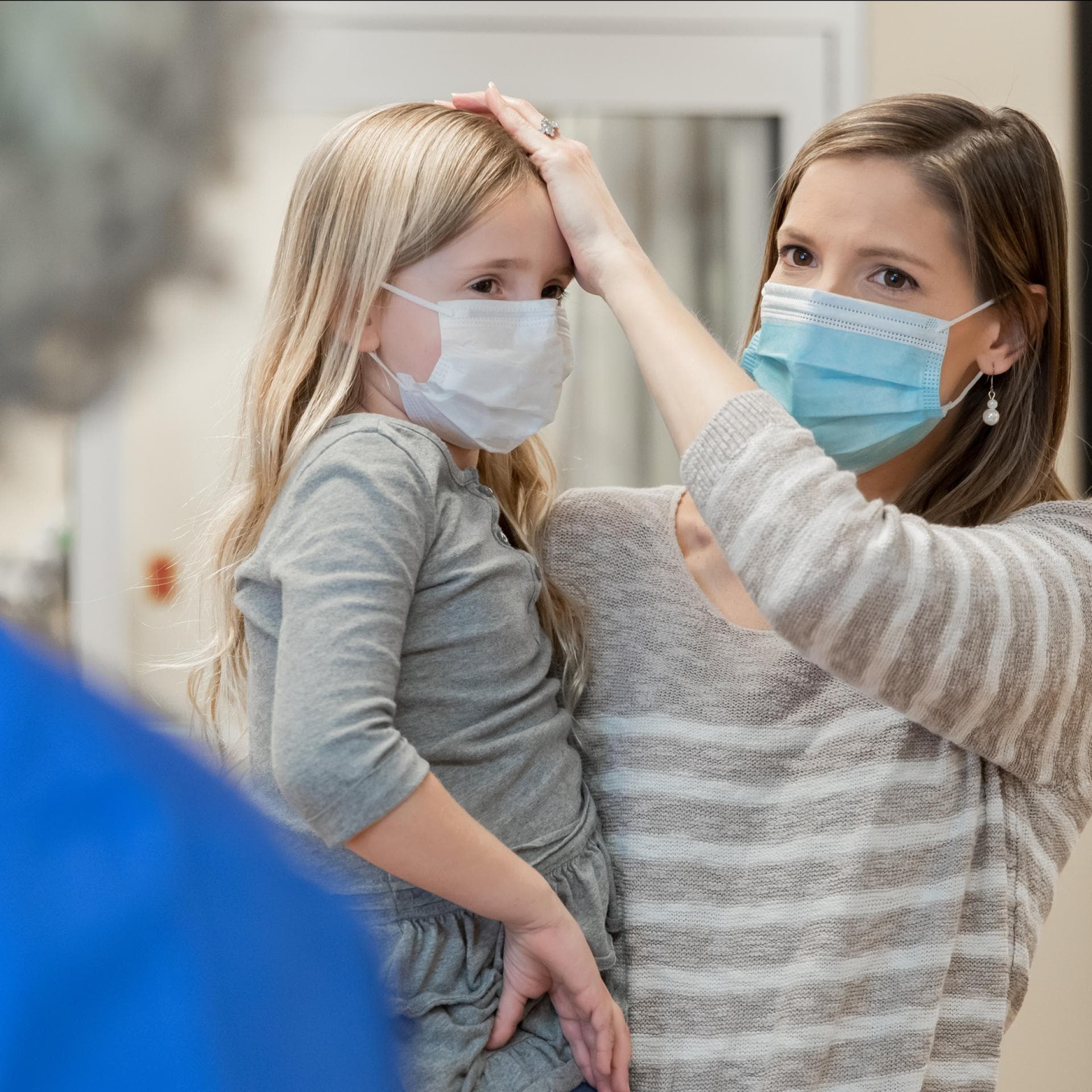 Mutter mit ihrer kranken Tochter am Empfang einer Kinderarztpraxis