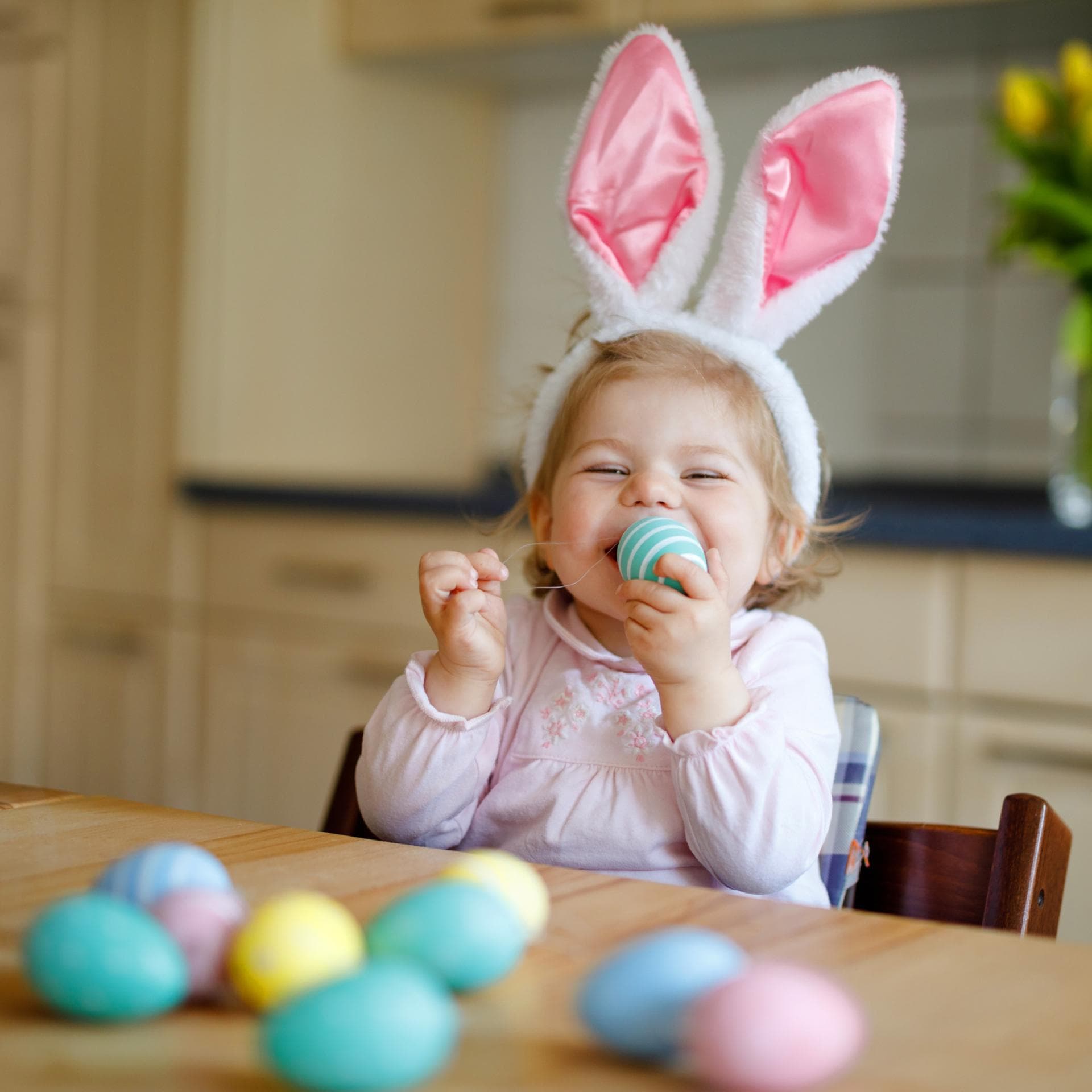 Ein kleines Mädchen lächelt und hat ein gefärbtes Osterei in der Hand.