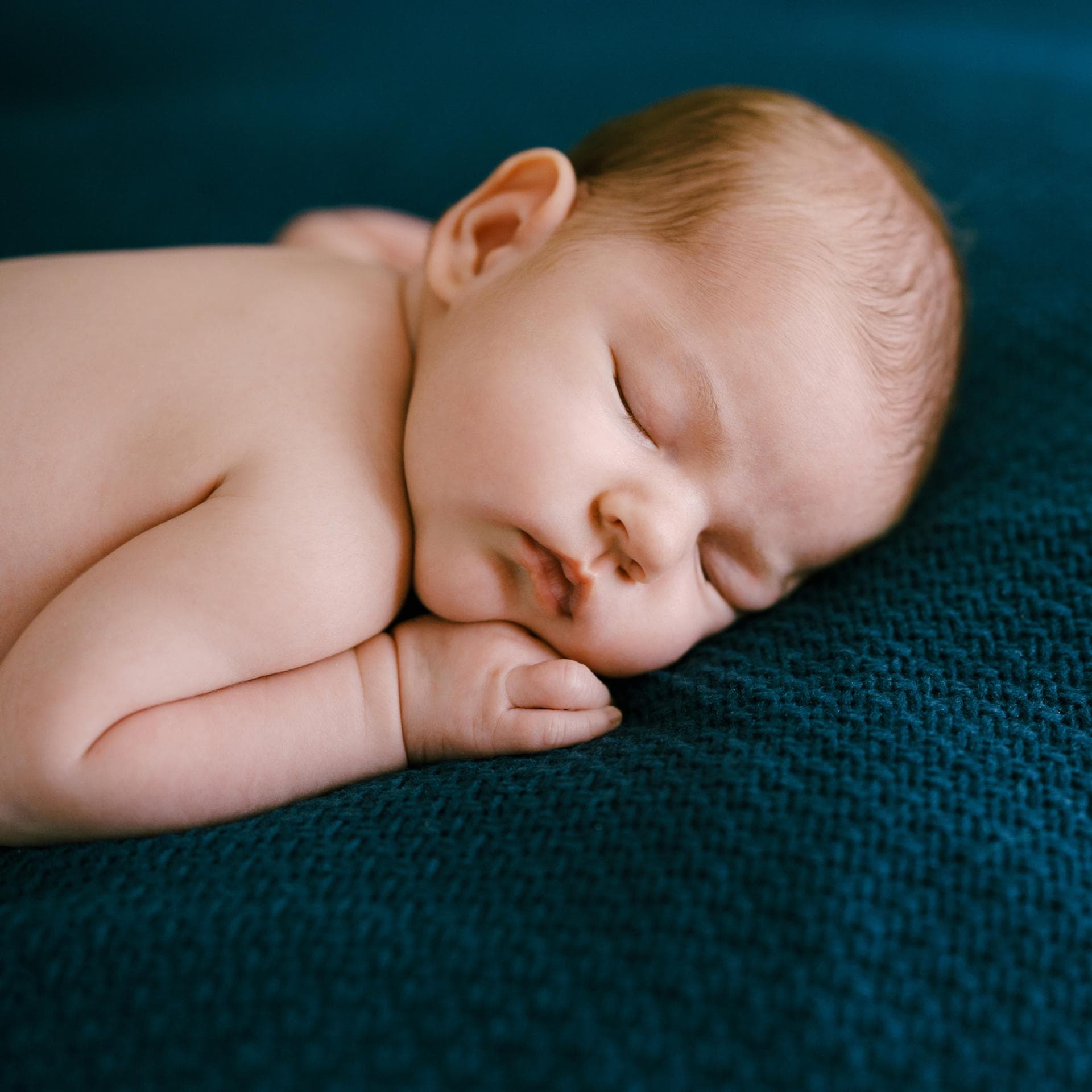 Ein Baby schläft in Bauchlage.