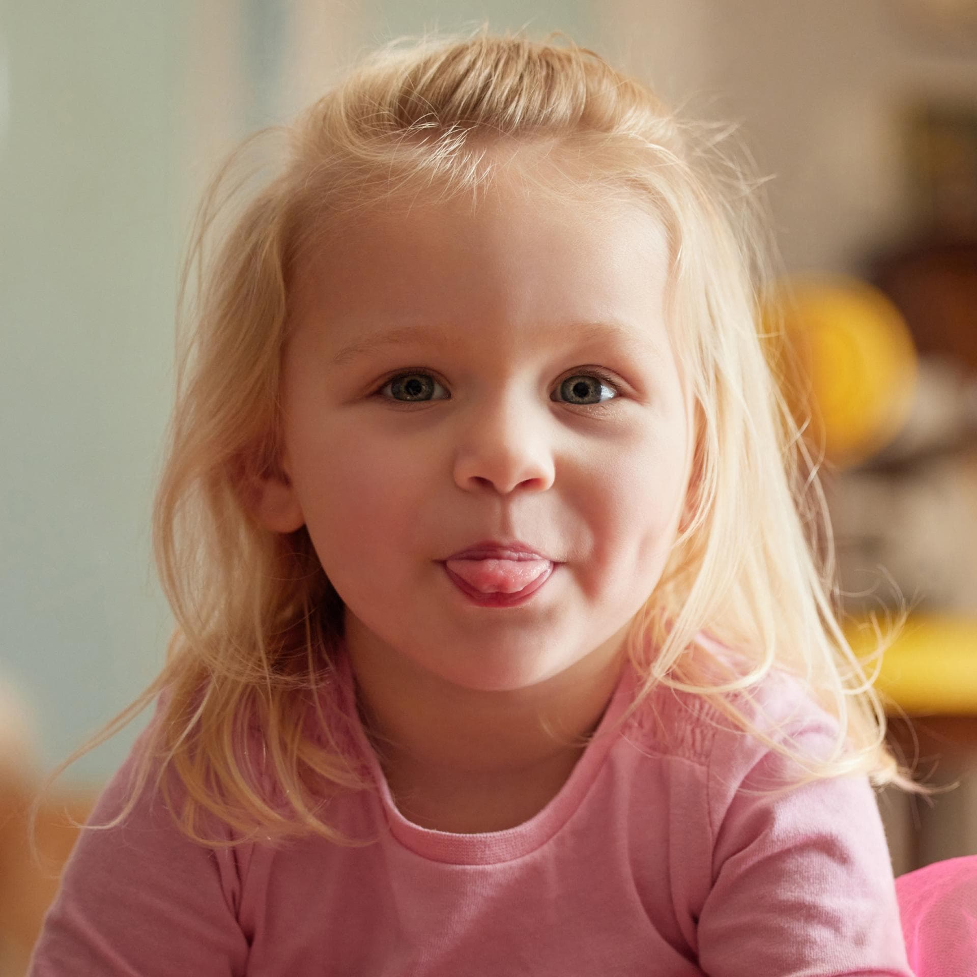 Ein kleines blondes Mädchen streckt die Zunge heraus.