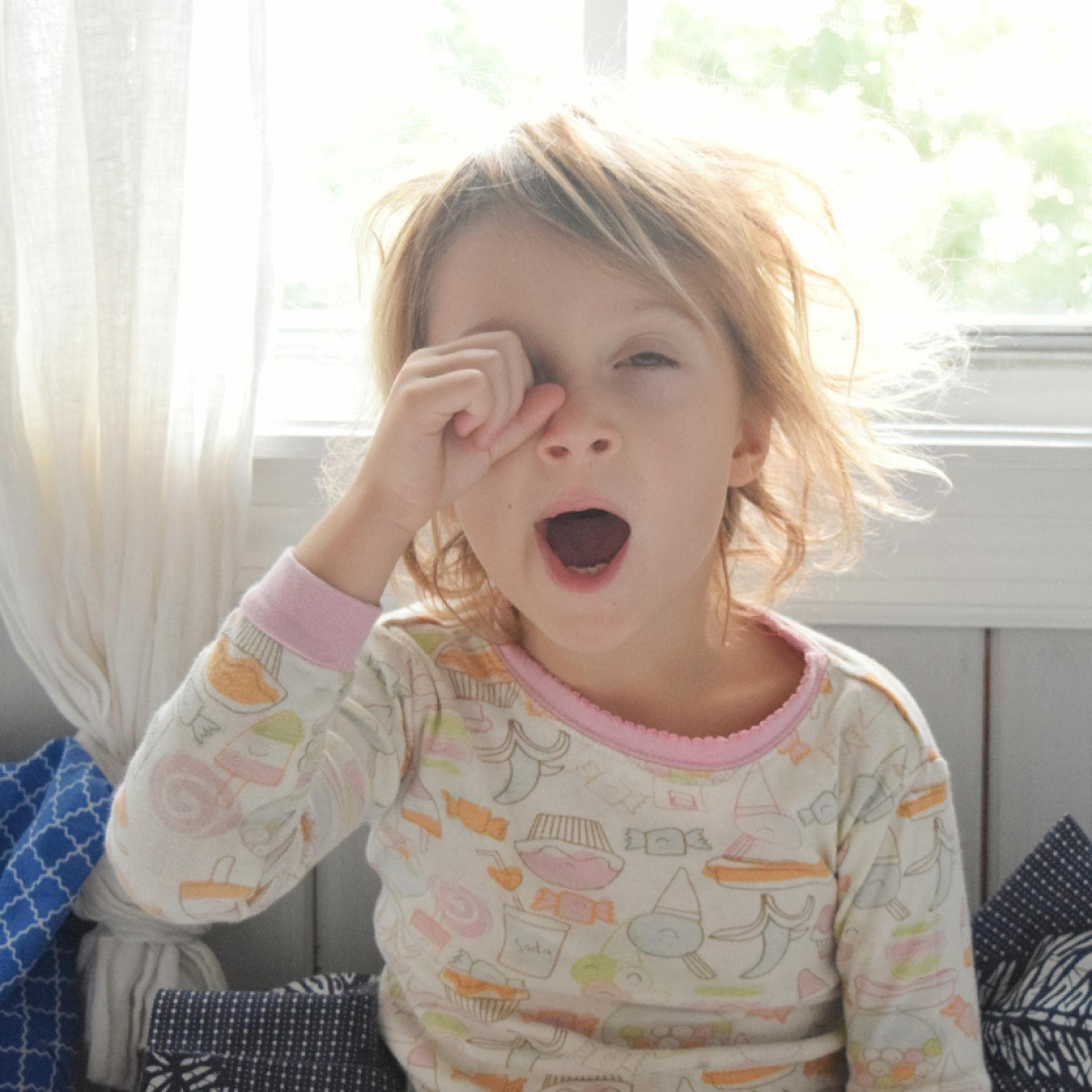 Blondes Mädchen reibt sich am Morgen die Augen und gähnt