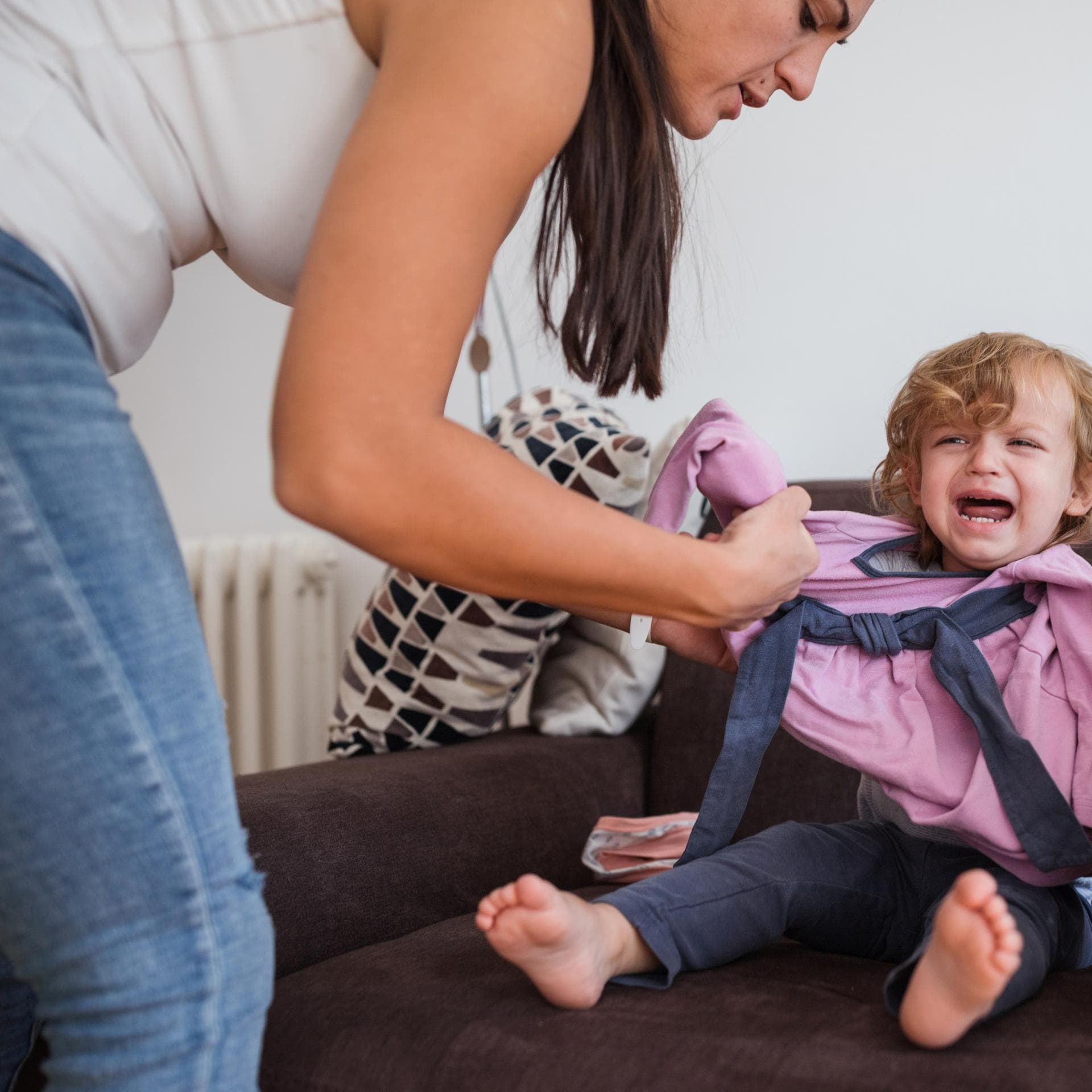 Mutter zieht weinendes Kind an.