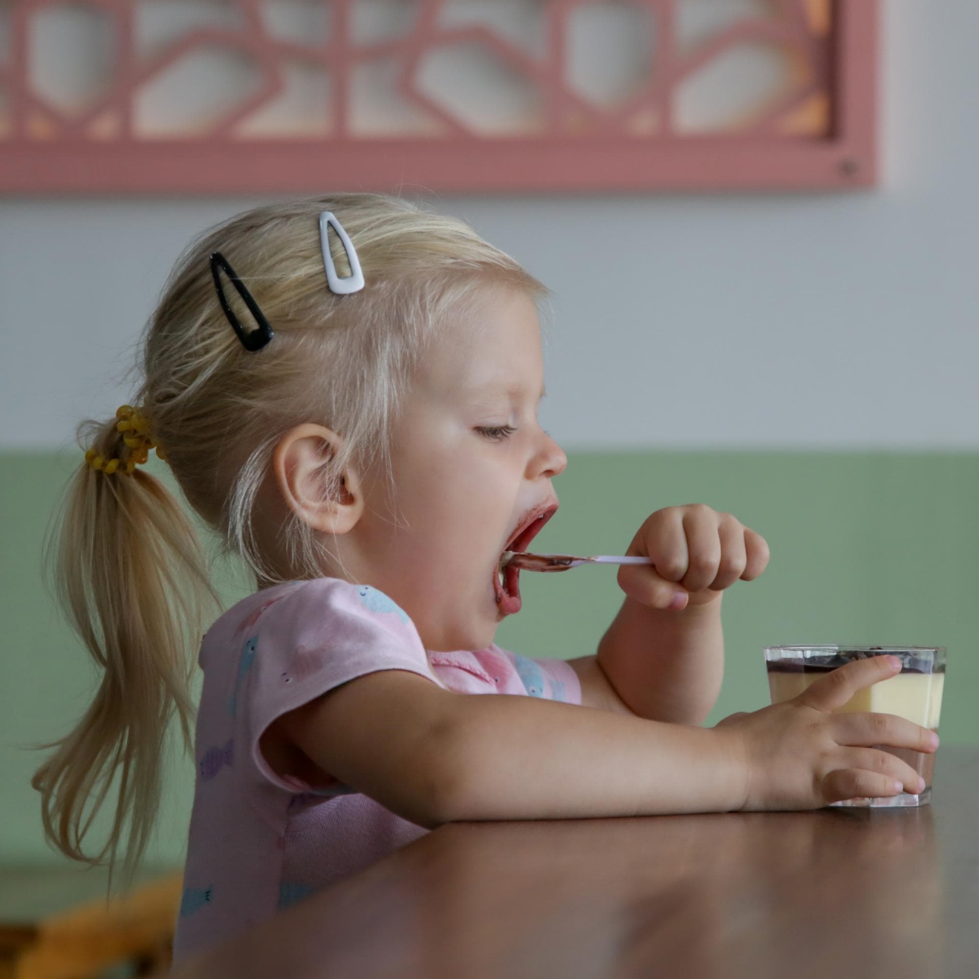Kleines Mädchen löffelt Dessert. 