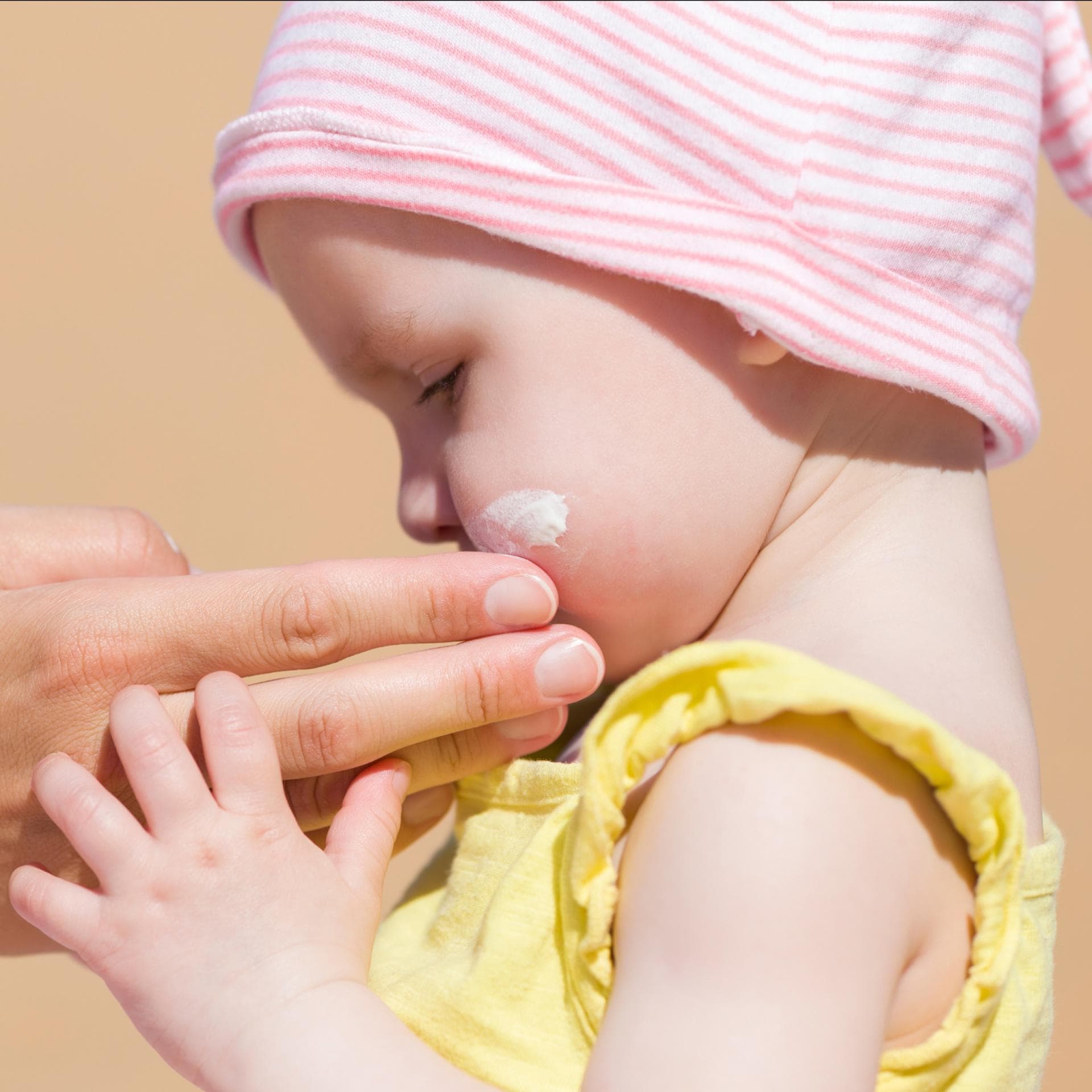 Kleines Kind mit Sonnencreme einschmieren