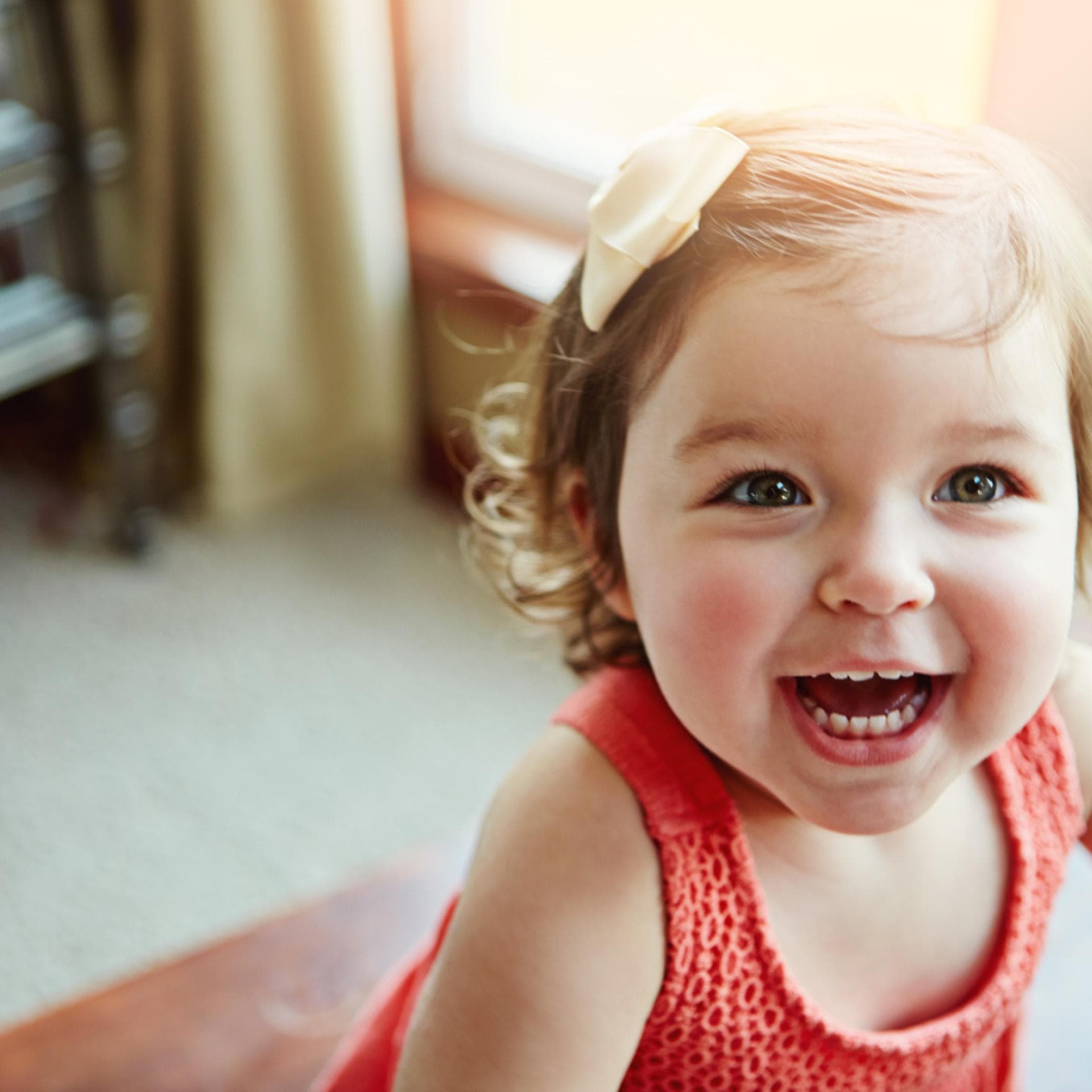 Kleines Baby-Mädchen lacht im hellen Licht der Sonne