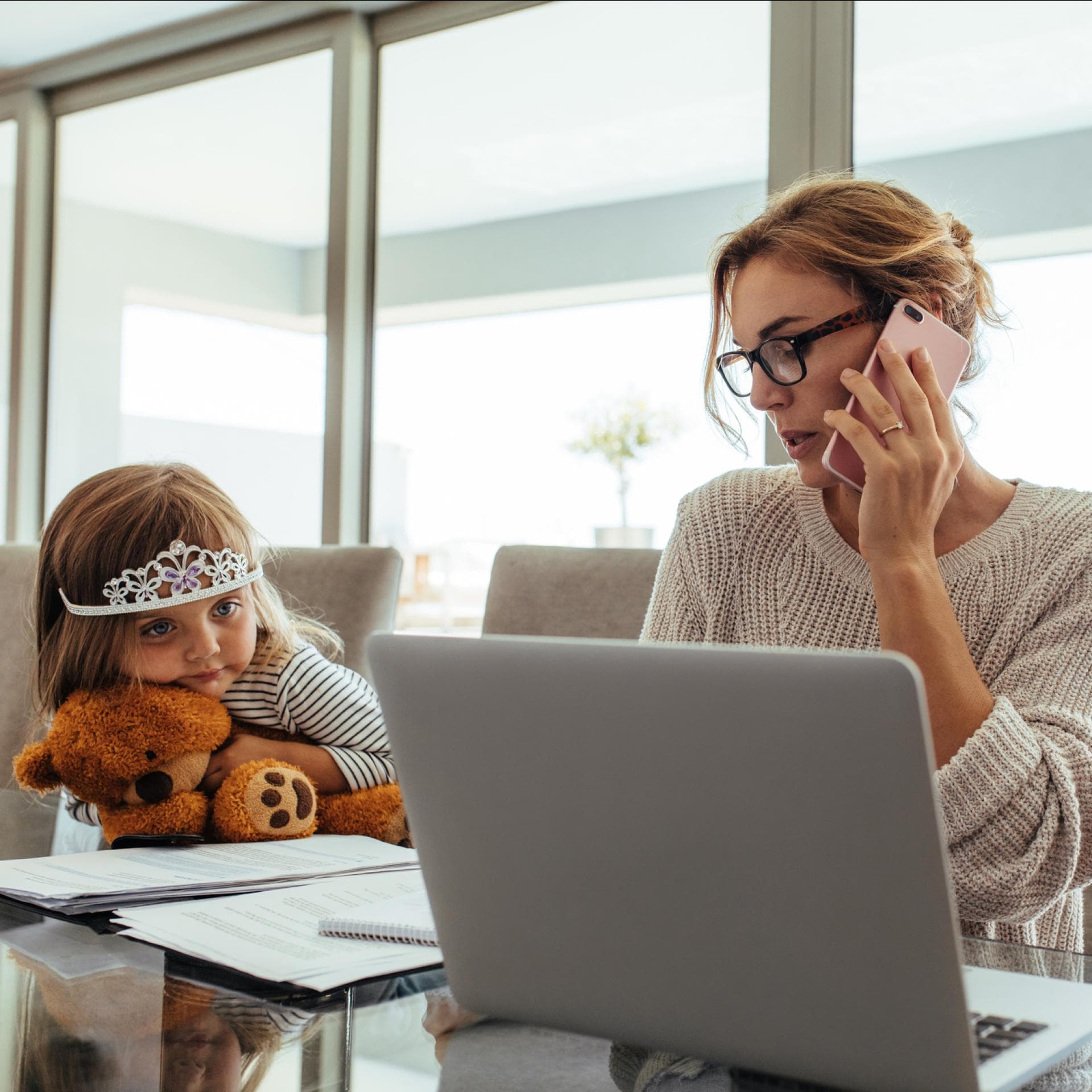 Eine Mutter, die am Laptop arbeitet, während ihre Kinder daneben sitzen.