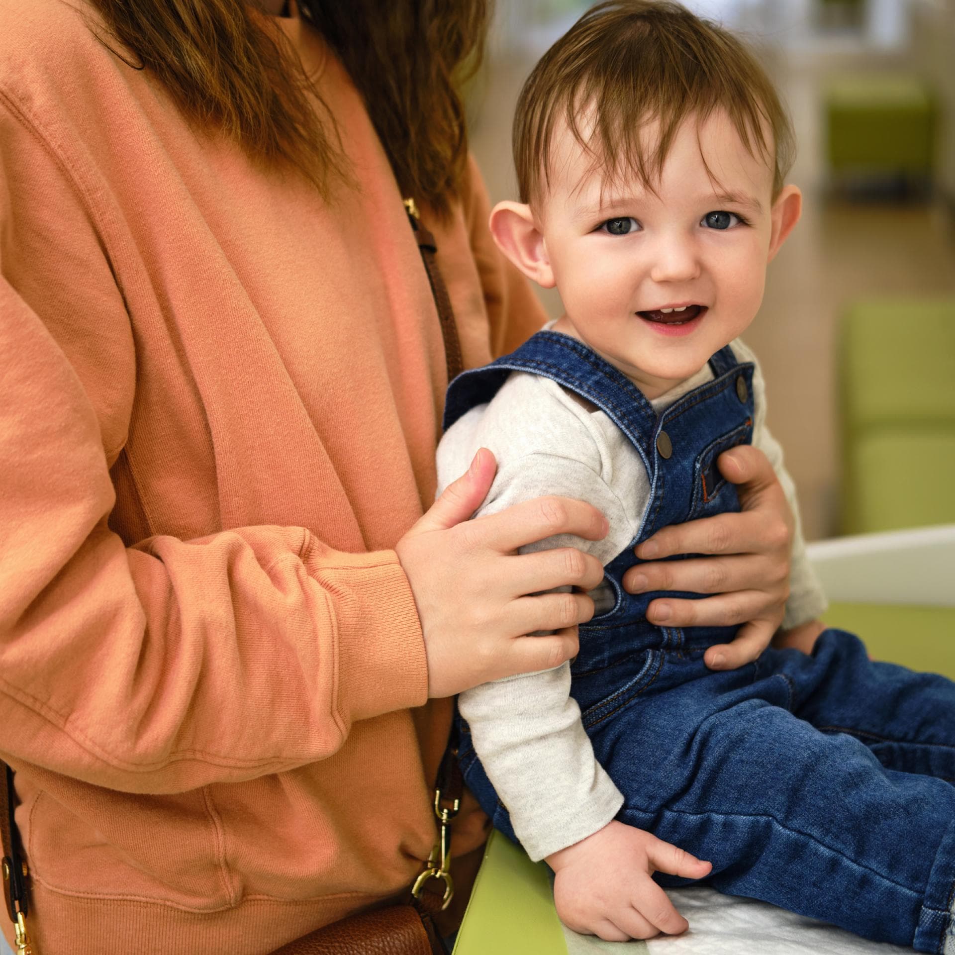 Mutter hält ihr sitzendes Kind auf dem Wickeltisch fest
