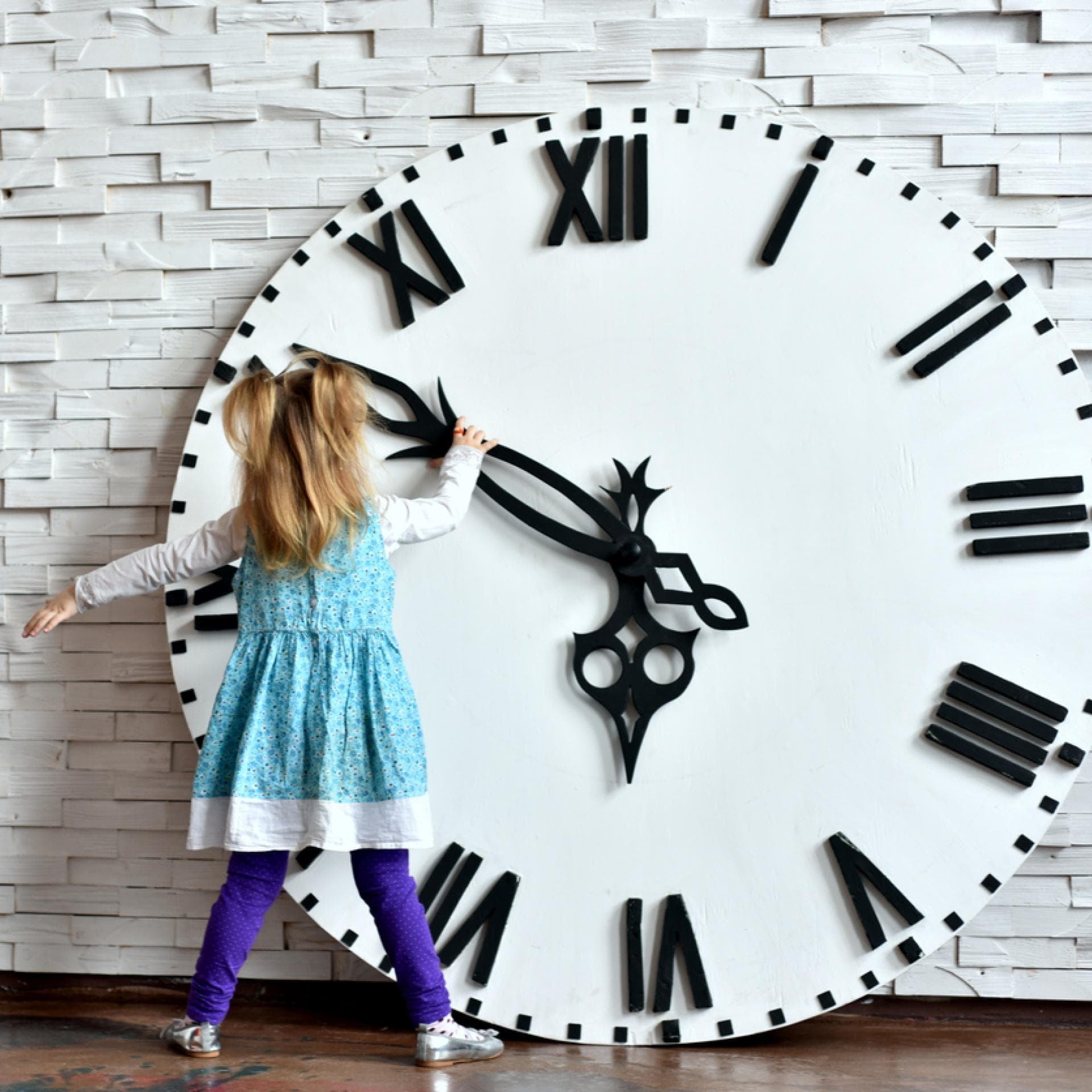 Kleines Mädchen steht vor riesiger Uhr