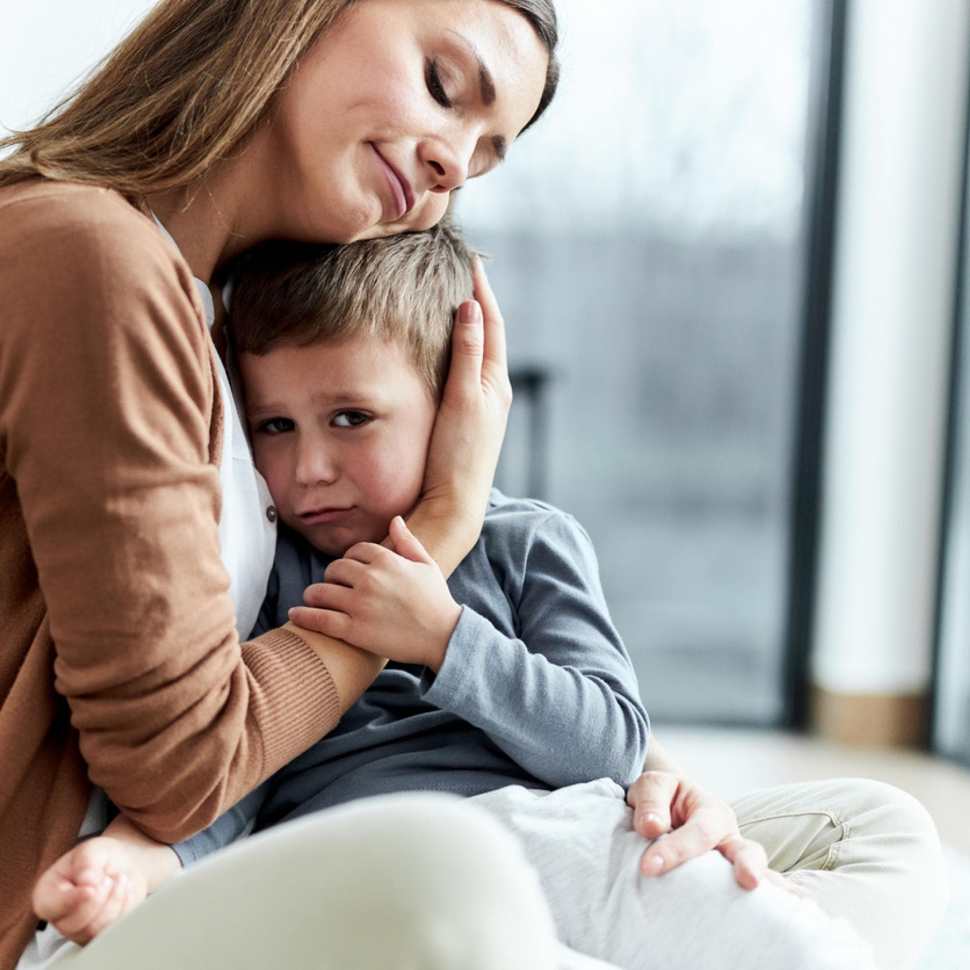 Liebevolle Mutter, die ihren traurigen Sohn zu Hause tröstet.