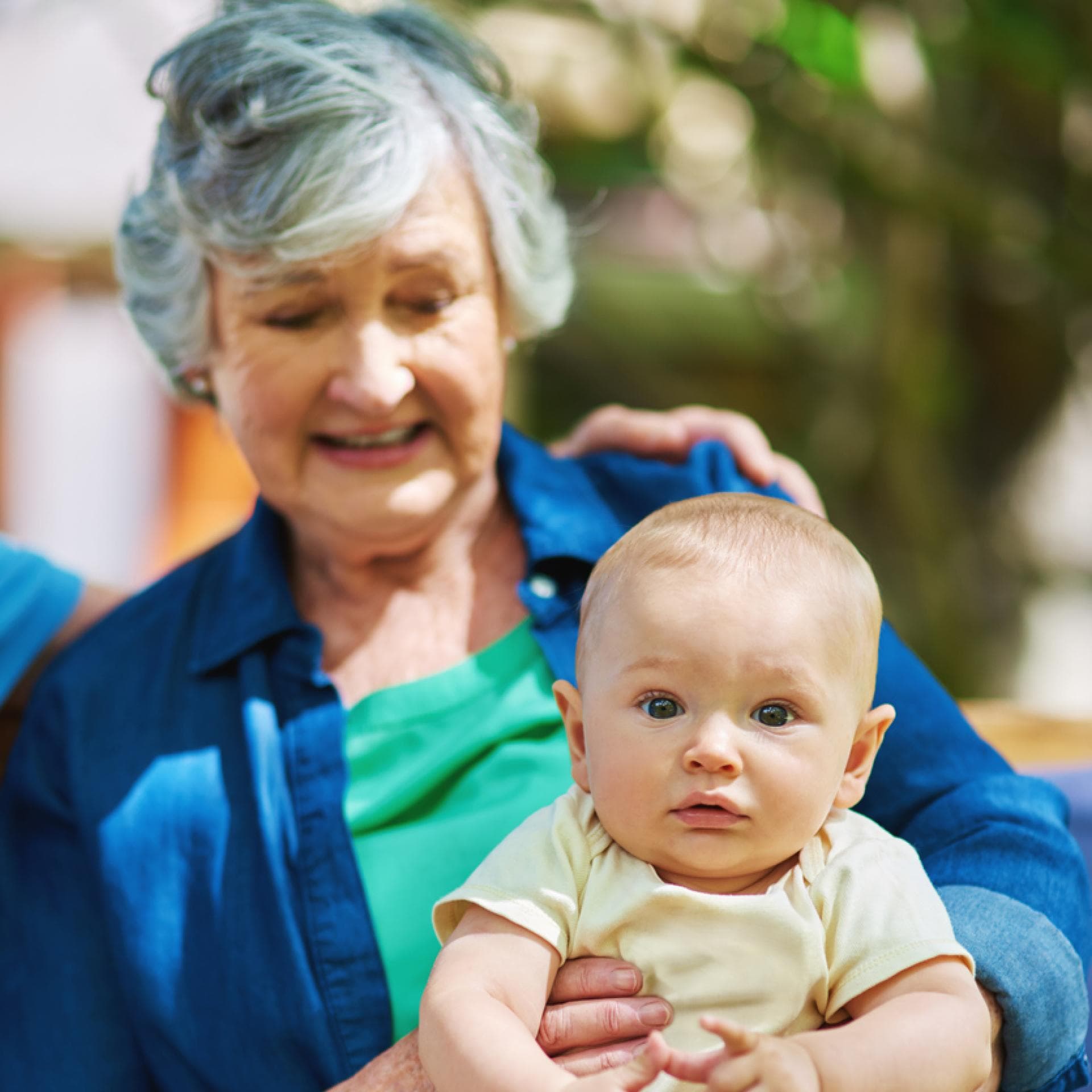 Baby sitzt bei Oma auf dem Schoss.