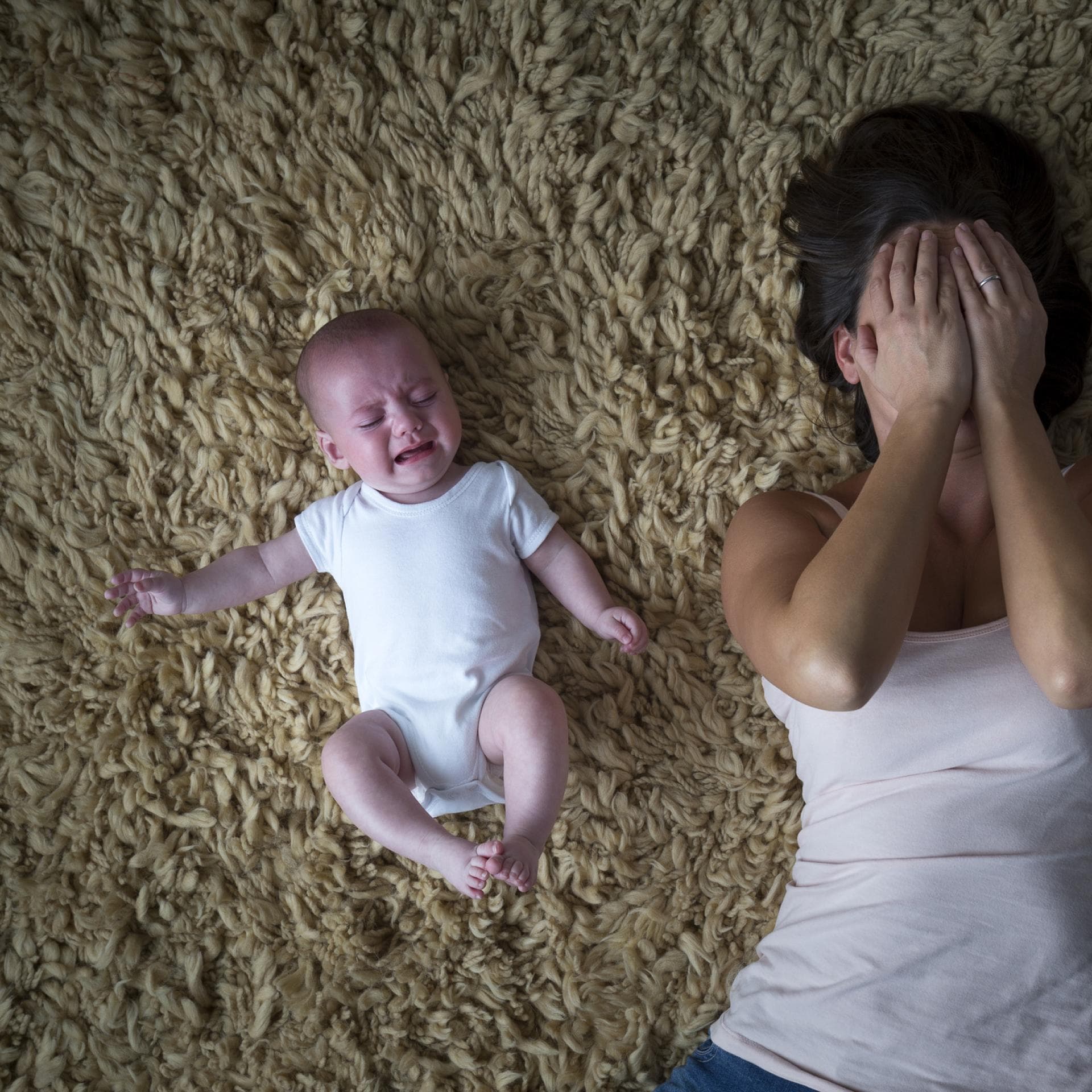 Mutter liegt weinend neben ihrem Baby auf dem Boden 