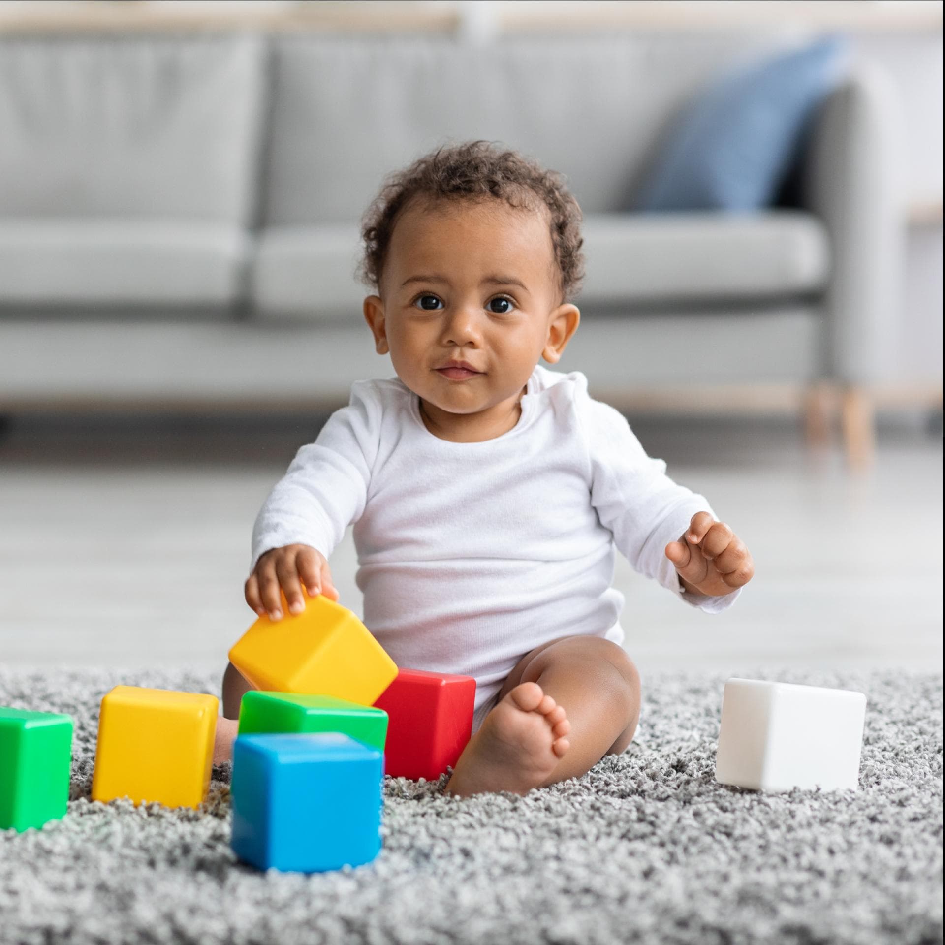 Ein kleiner Junge sitzt auf dem Boden und spielt mit Bauklötzen.